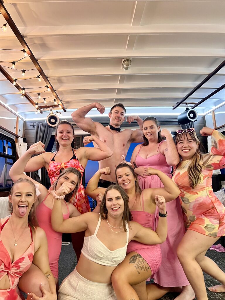 group of girls flexing biceps with a topless waiter